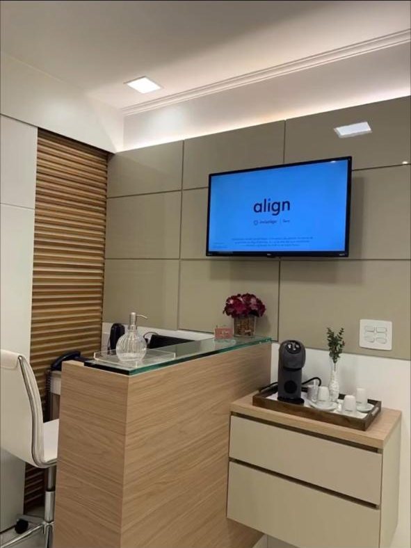 Recepção do consultório com balcão e TV